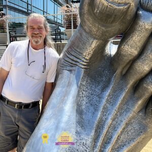 Photo of Don standing next to a large cast foot at National Harbor